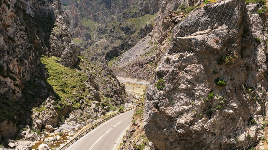 Aerial drone view of a mountain road winding between the steep rocky cliffs of a rugged canyon, Kourtaliotiko Gorge, Greece