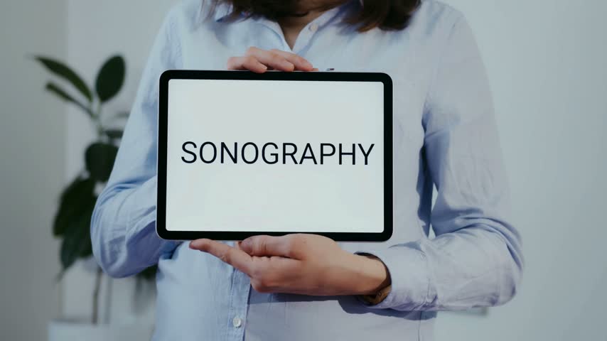 Health professional shows sonography. Medical expert displays text images on tablet in clinic setting. Bright room with modern decor suggests health and wellness environment. Focus on patient care.