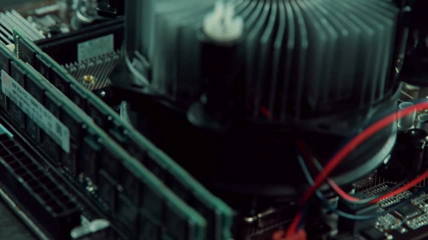closeup Detailed view of a PC motherboard featuring RAM, a metal heatsink processor fan, and complex electronic circuits, showcasing modern hardware technology.