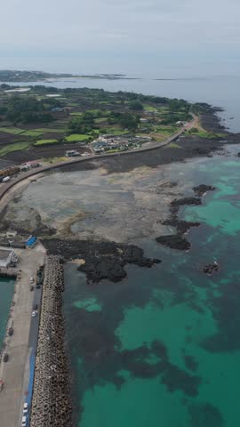 Turquoise Ocean, Dark Basalt Volcanic Rocks And A Concrete Breakwater Along The Jongdal-ri Coast In Jeju Island, South Korea. - aerialv ertical shot