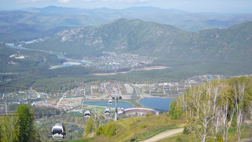 Manzherok resort alpine valley panorama with moving cable car cabins in autumn.