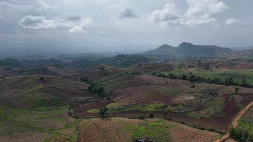 Beautiful aerial perspective of undulating hills leading toward a hazy mountain skyline.