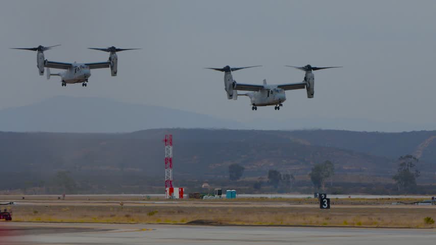 Two osprey aircraft hovering with vertical propellers at an airshow