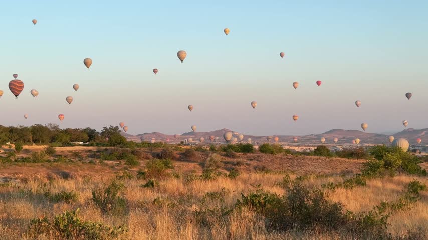 Many hot air balloons flying over Cappadocia at sunrise, Turkey.