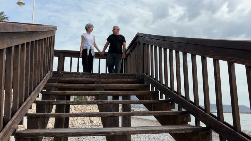 Mature couple walking down wooden steps to the beach