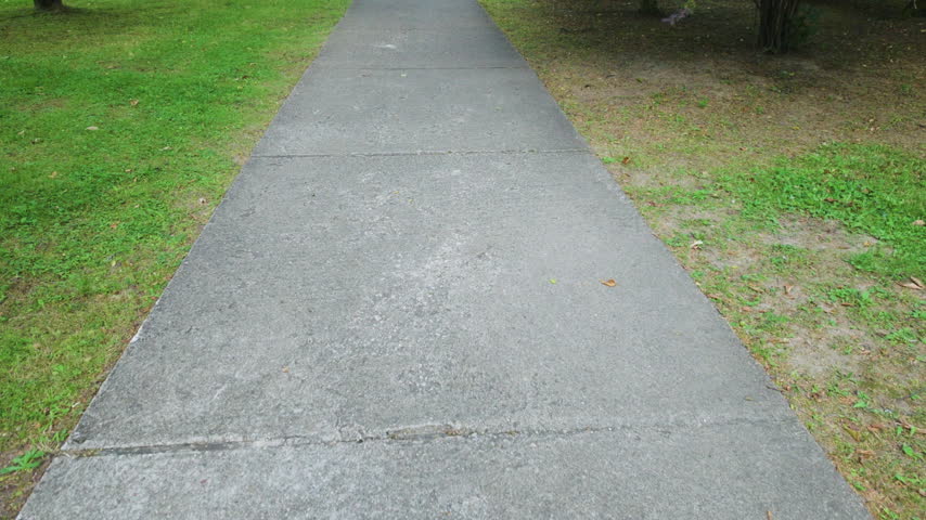 Walking along concrete pathway in green park
