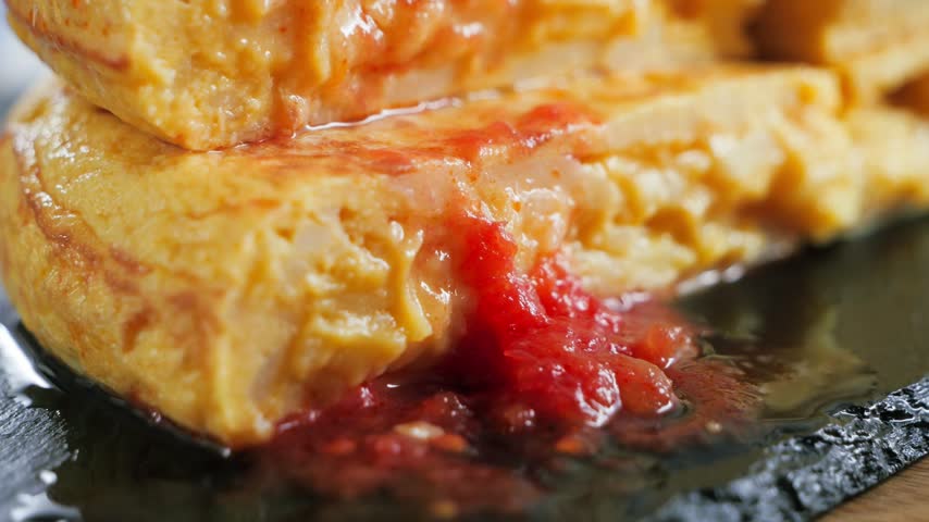 Spanish potato omelette Tortilla de patatas, slices topped with grated tomato sauce close up.