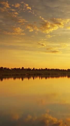 a peaceful lake scene during sunset with a vibrant orange sky and calm water reflecting the colors of the sky, ideal for relaxation, travel, or nature-related marketing
