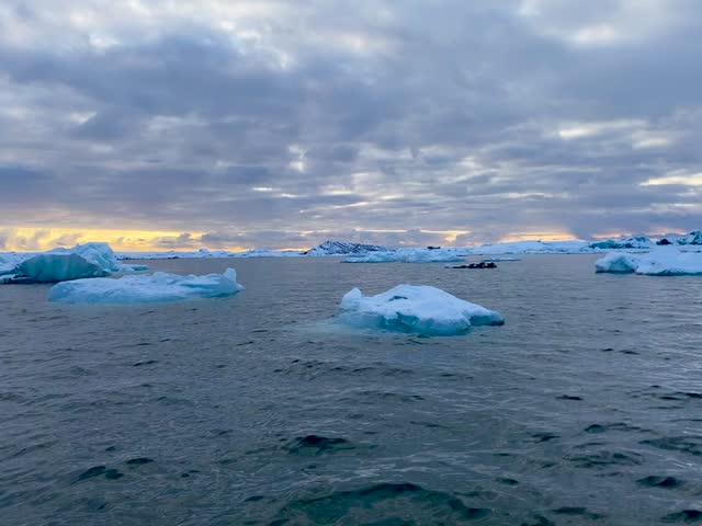 RIB boat tour among floating icebergs at sunrise on Jökulsárlón glacier lagoon, Iceland, winter
Vertical video shot from a rigid inflatable boat sailing across Jökulsárlón glacier lagoon in southern Iceland at sunrise in November. Floating icebergs drift on calm blue water with snow-covered mountains in the background, while frost covers the edge of the boat. A cold, serene winter atmosphere, ideal for Iceland travel, adventure tourism, climate and nature concepts.