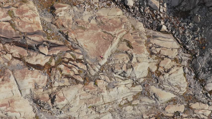 Aerial view of Aletsch Glacier rocky terrain with a person lying on the stone surface in Fieschertal, Valais, Switzerland.
