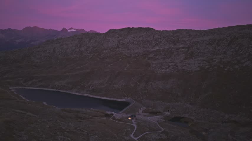 Aerial view of Aletsch Glacier and mountain lake under a purple twilight sky in Fieschertal, Valais, Switzerland.