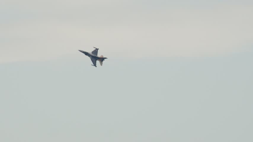 F16 Fighting Falcon military aircraft performing a high speed maneuver. The powerful fighter jet is flying in a clear sky