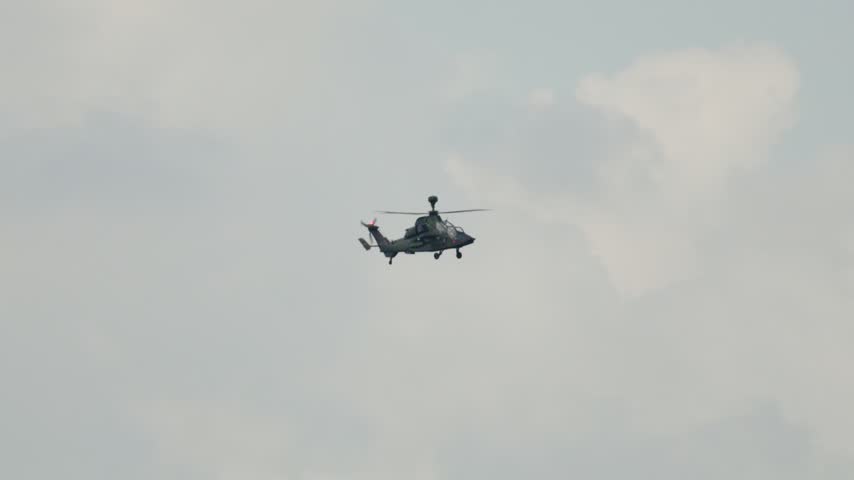Military attack helicopter, the Eurocopter Tiger, flying during a mission. The modern gunship is hovering against a cloudy sky