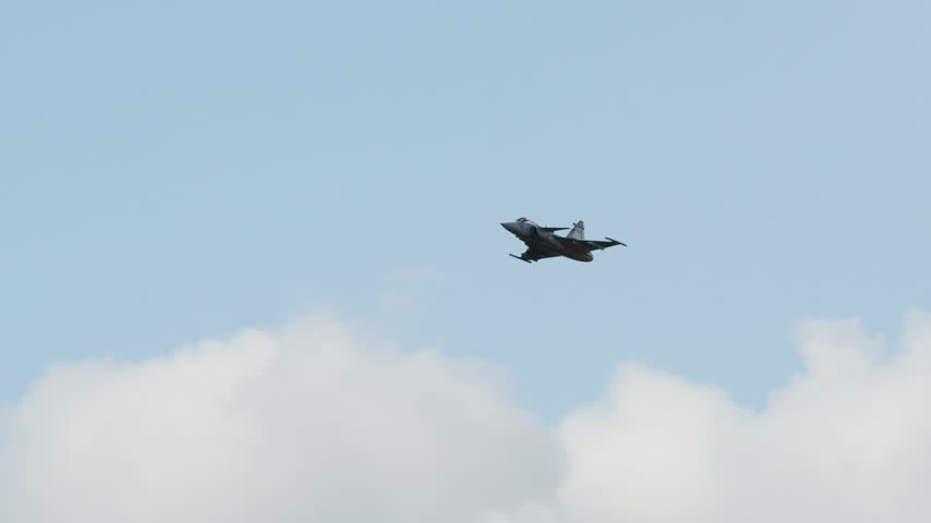 Military Saab JAS 39 Gripen aircraft performing a demonstration flight. Supersonic fighter plane flying against a clear blue sky