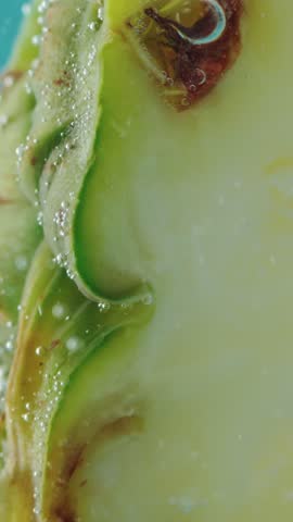 Juicy pineapple fruit stays submerged underwater against bright blue backdrop. Rising air bubbles flow past textured pineapple peel, highlighting refreshing freshness and natural sweetness.