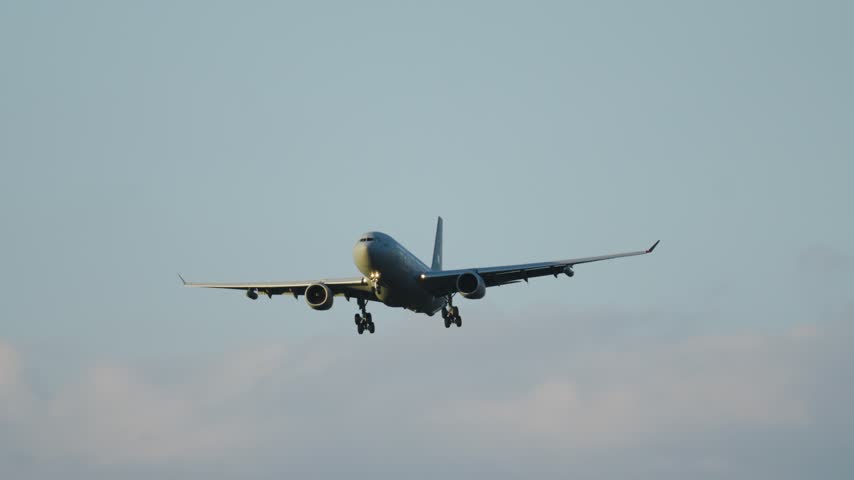 Large military transport aircraft on its final approach for landing at an airport. The landing gear is down, preparing for touchdown