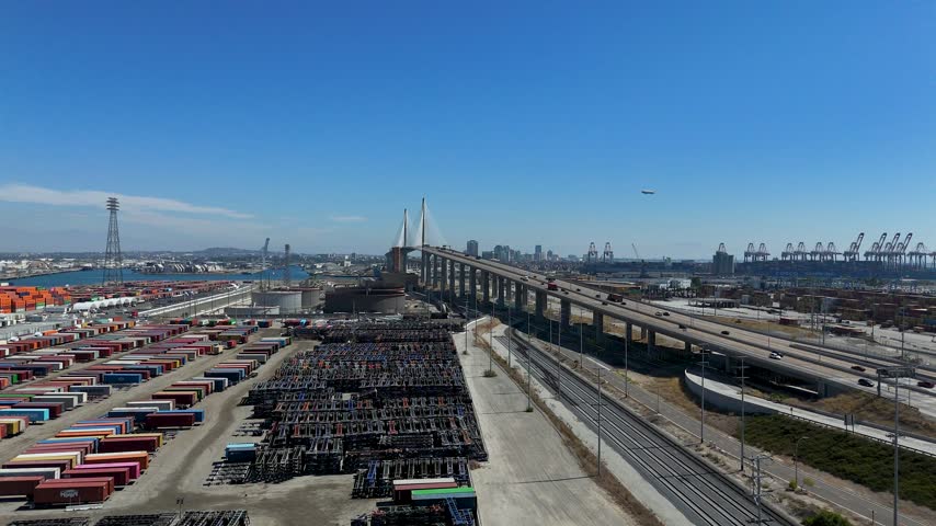 Aerial view of the Port of Long Beach featuring the Gerald Desmond Bridge, shipping containers, and industrial infrastructure in Long Beach, California, United States.