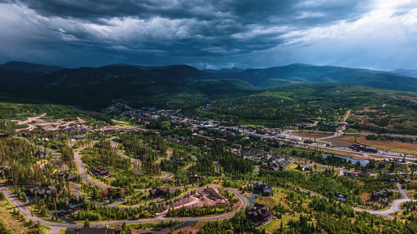 Aerial view of the town of Granby nestled in the mountains of Colorado under a dramatic stormy sky with winding roads and evergreen forests. Granby, Colorado, United States.