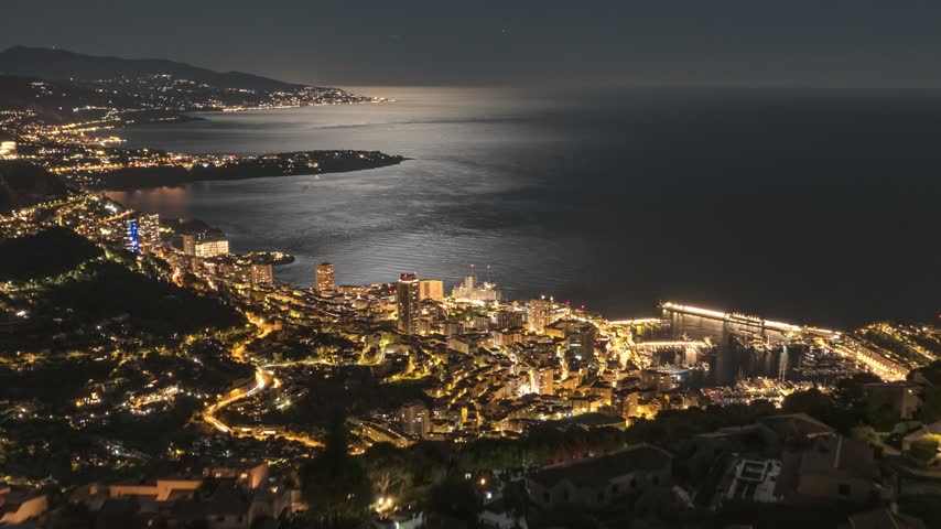 Aerial view of the illuminated cityscape of Monaco at night, featuring the harbor, coastal buildings, and the Mediterranean Sea, Monaco, Monaco.