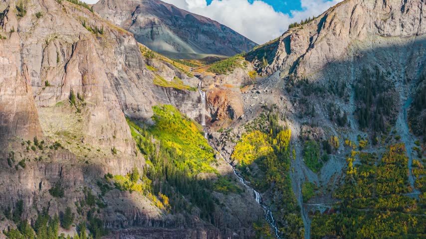 Aerial view of Bridal Veil Falls cascading down rocky cliffs surrounded by vibrant autumn foliage in Telluride, Colorado, United States.
