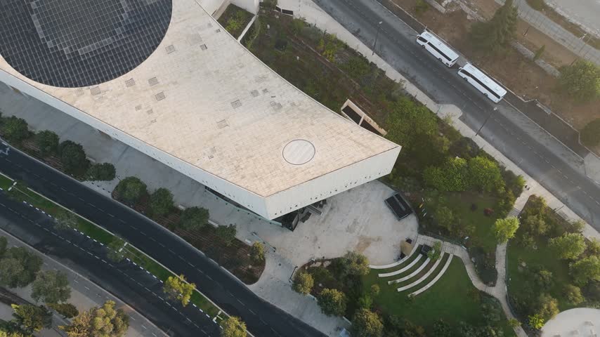 Aerial view of the National Library of Israel featuring modern architecture, stone roof, and circular skylight, surrounded by gardens in Jerusalem, Jerusalem District, Israel.