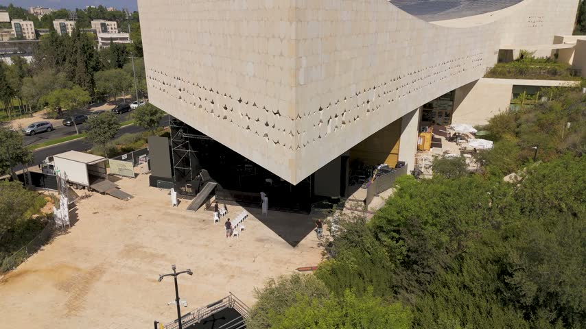 Aerial view of the modern National Library of Israel building featuring unique stone architecture surrounded by lush greenery and urban landscape in Jerusalem, Jerusalem District, Israel.