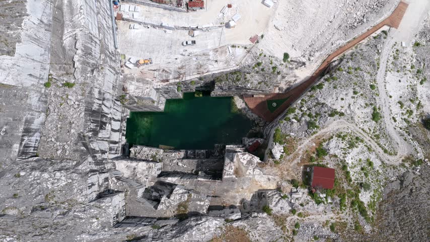 Aerial view of the Carrara marble quarry with its deep green water and white stone walls in Carrara, Tuscany, Italy.