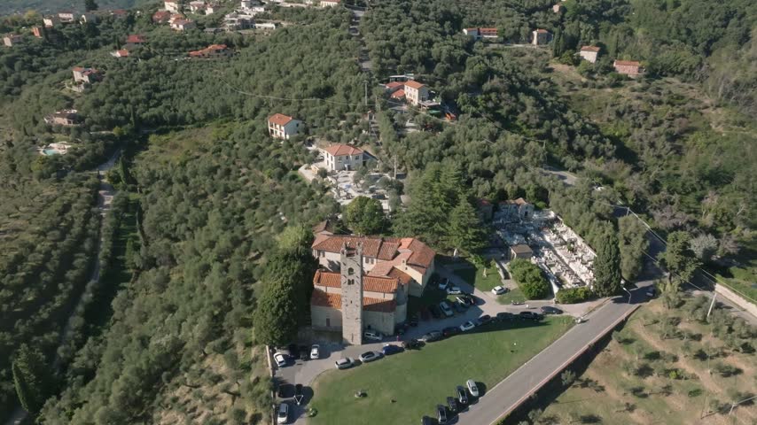 Aerial view of the historic Chiesa di San Pantaleone in Pieve a Elici, surrounded by olive groves and rolling hills in Massarosa, Toscana, Italy.