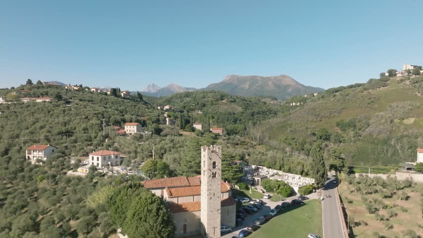 Aerial view of Chiesa di San Pantaleone in Pieve a Elici surrounded by olive groves and rolling hills in Massarosa, Toscana, Italy.