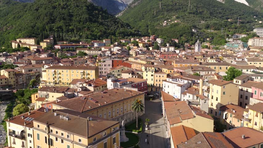 Aerial view of Carrara city center with historic buildings, terracotta rooftops, and surrounding mountains in Carrara, Tuscany, Italy.