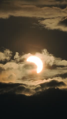 Stunning astronomical event showing the August 12, 2026, partial solar eclipse, with the moon passing in front of the sun, creating a celestial spectacle behind dramatic dark clouds