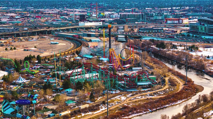 Aerial view of Elitch Gardens Theme Park with roller coasters and water slides near the South Platte River and urban infrastructure in Denver, Colorado, United States.
