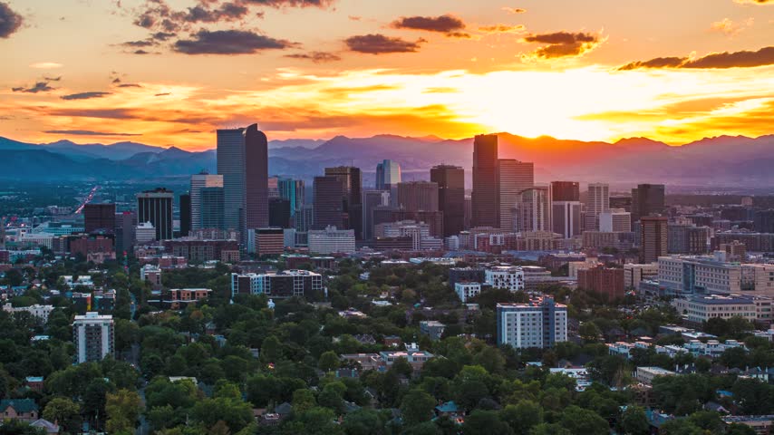 Aerial view of the Denver skyline at sunset with skyscrapers and mountains in the background in Denver, Colorado, United States.
