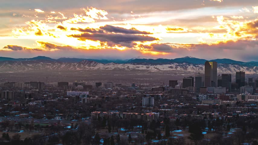 Aerial view of the Denver skyline at sunset with the snow-capped Rocky Mountains in the background in Denver, Colorado, United States.