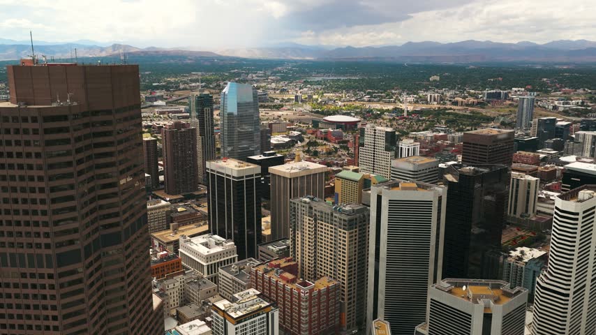 Aerial view of Denver city skyline with modern skyscrapers and urban architecture under a cloudy sky in Denver, Colorado, United States.