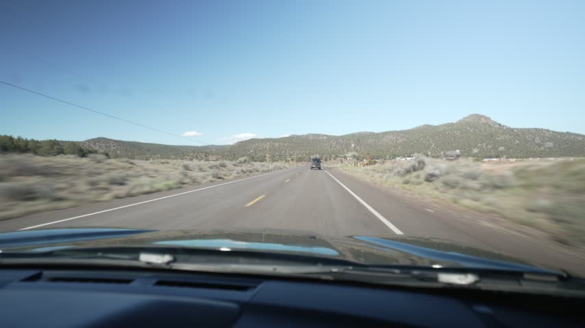 Driving POV on a rural highway toward forested hills in Central Oregon