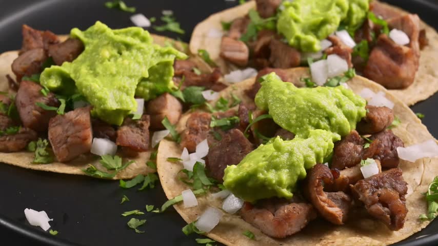 Close up view of Mexican grilled beef tacos with creamy guacamole and chopped fresh cilantro