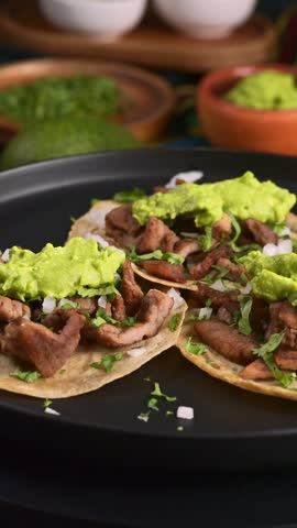 Authentic Mexican carne asada tacos served with fresh guacamole, onions, and cilantro