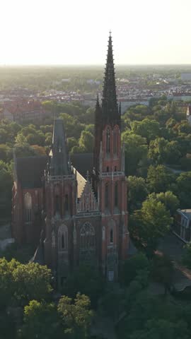 Aerial view of Gothic cathedral tower in Wroclaw, Poland, surrounded by cityscape, showcasing intricate architecture and vibrant urban greenery