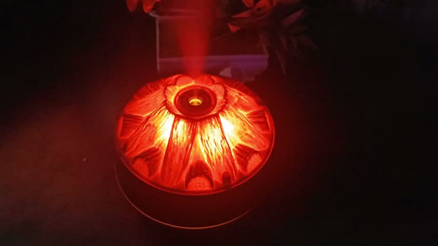 Top view of volcano mist diffuser crater glowing red with steam rising