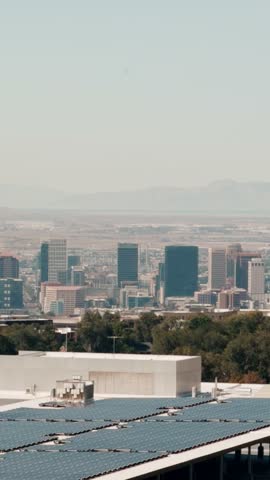Static portrait view of the Salt Lake City skyline beyond a rooftop and tree canopy.