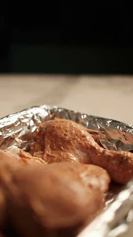Marinated chicken drumsticks being placed into a foil-lined baking tray, showing hands-on meal preparation before oven cooking and a homemade family dinner.