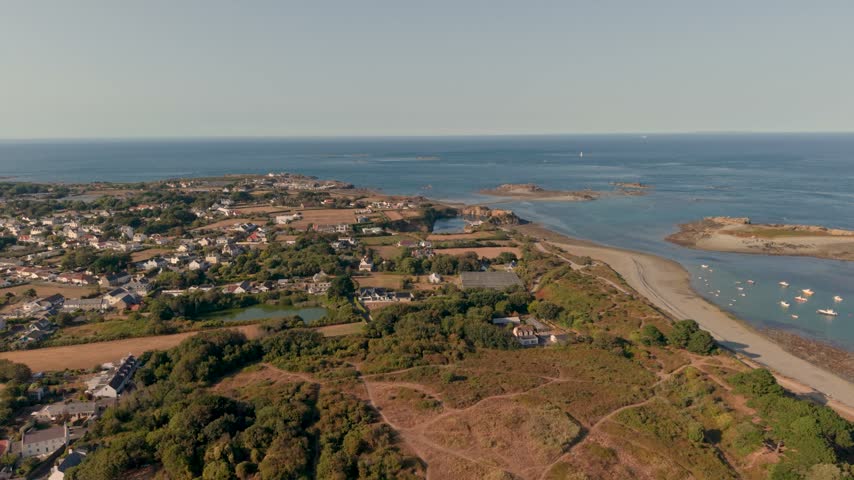 Guernsey Channel Islands,drone flight over North East Coastline with calm clear sea,and boats at anchor,panning across to Herm over Little Russell Channel on bright sunny day with blue sky