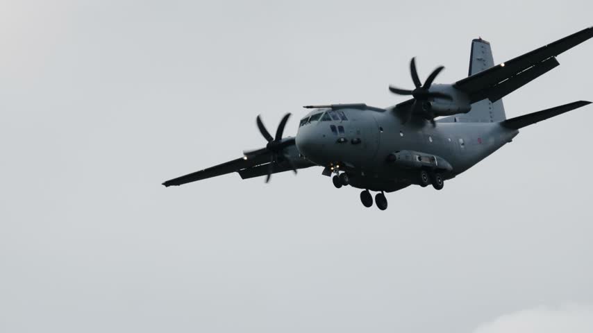 Large military transport aircraft Alenia C 27 Spartan flying against a grey sky. The airplane is on final approach with landing gear down