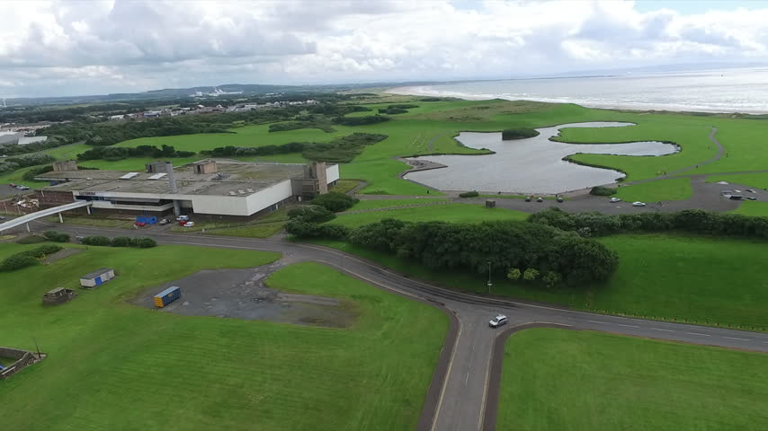 Drone Push In Shot Flying Across Irvine Beach Park Pavilion Toward Large Scenic Pond in Scotland