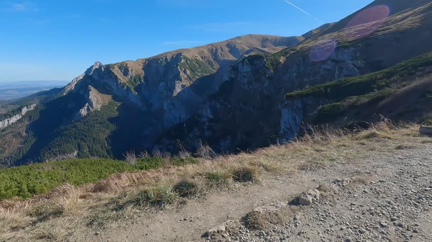 Steep rocky cliff drops below a grassy high ridge on the Czerwone Wierchy approach