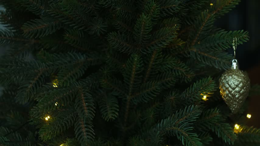 Woman decorating Christmas tree with Christmas bauble.