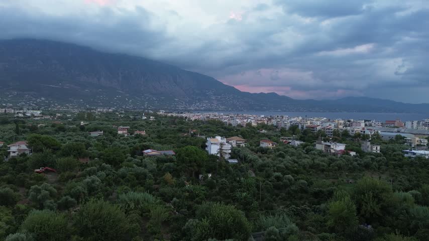 Aerial pan of Kalamata, Greece with Taygetos mountain under a cloudy dusk sky