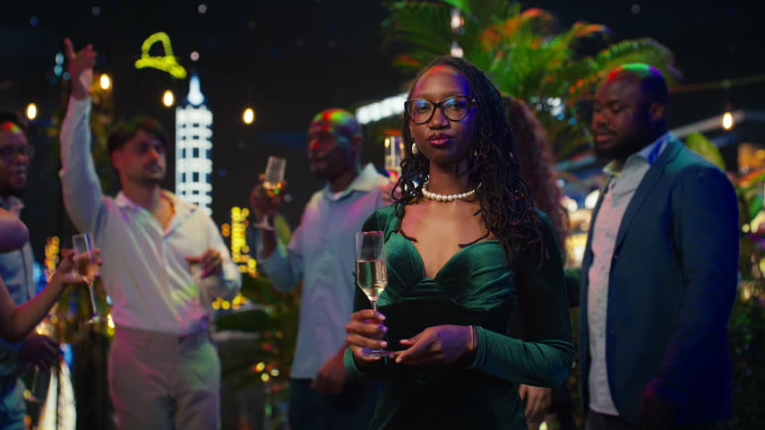 Woman raising champagne glass in celebratory toast during New Year Eve, with confident African american woman surrounded by group of friends raising sparkling wine flute