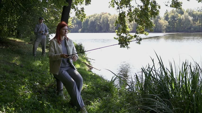 An angler is fishing for pike on a lake. A tense moment as a large predatory fish strikes; the struggle with the catch set against the backdrop of a picturesque forest lake.